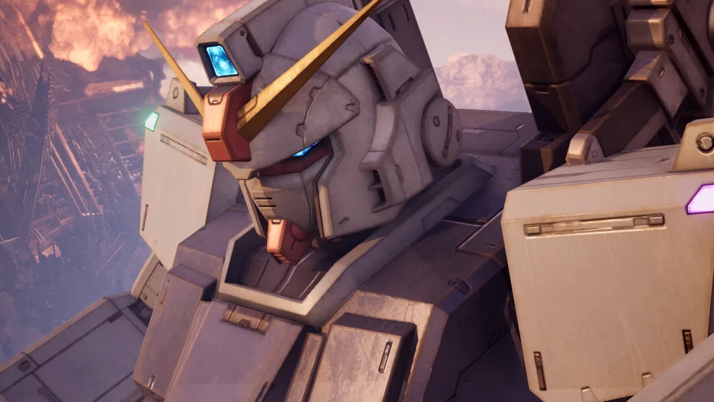 Close-up of a weathered white Gundam head with a yellow V-fin and glowing blue eyes, with a burning city structure in the background.