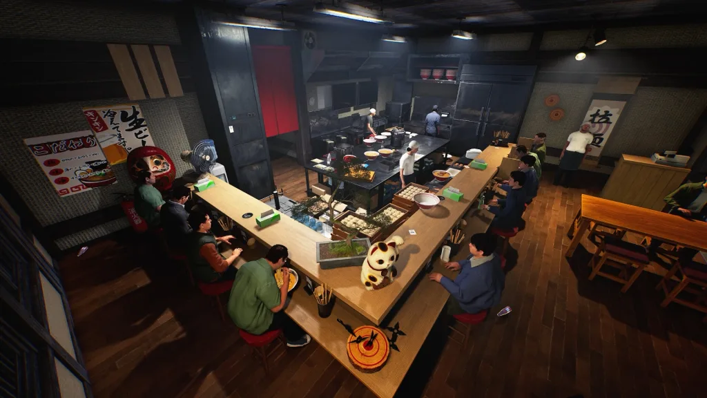 Overhead view of a Japanese ramen shop: a cook behind a U-shaped counter and customers seated on red stools, with a maneki-neko cat on the counter.